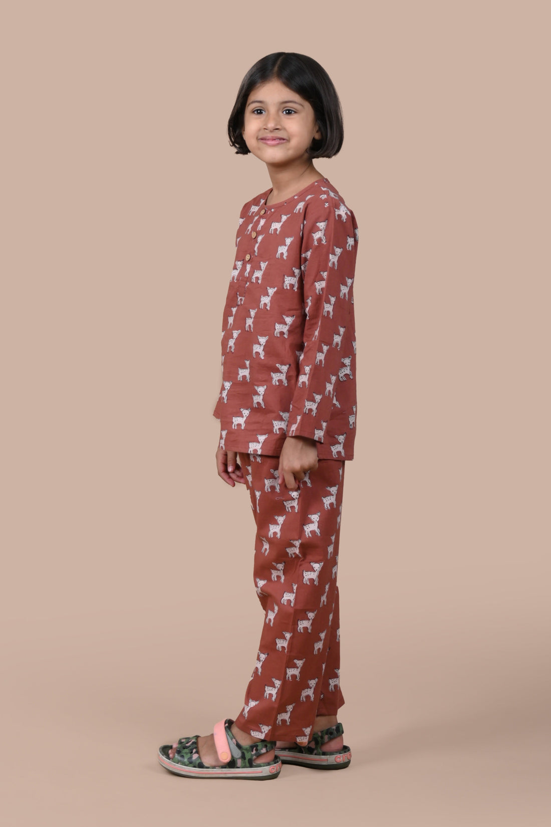Child wearing a brown pajama set with animal pattern on a beige background