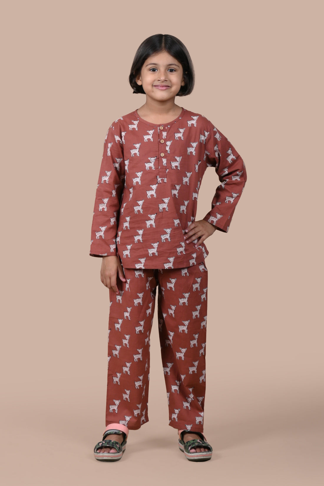 Child wearing a brown pajama set with animal pattern on a beige background