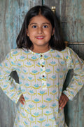 Young girl wearing a floral-patterned nightsuit with a wooden door in the background