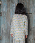 girl wearing a floral pajama set standing in front of a textured wall.
