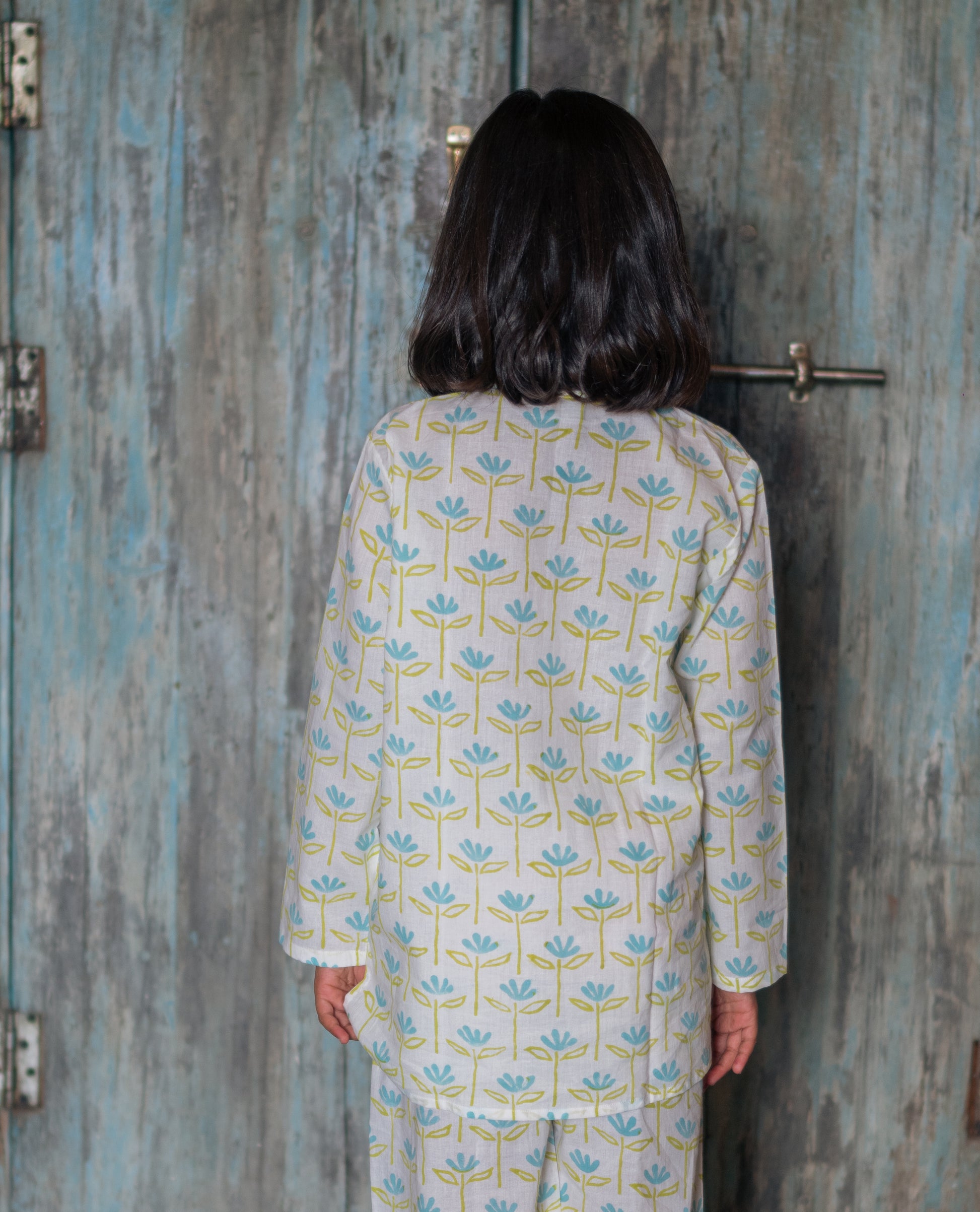 girl wearing a floral pajama set standing in front of a textured wall.