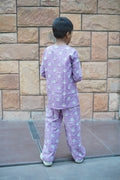 Child in purple pajamas standing on a tiled floor