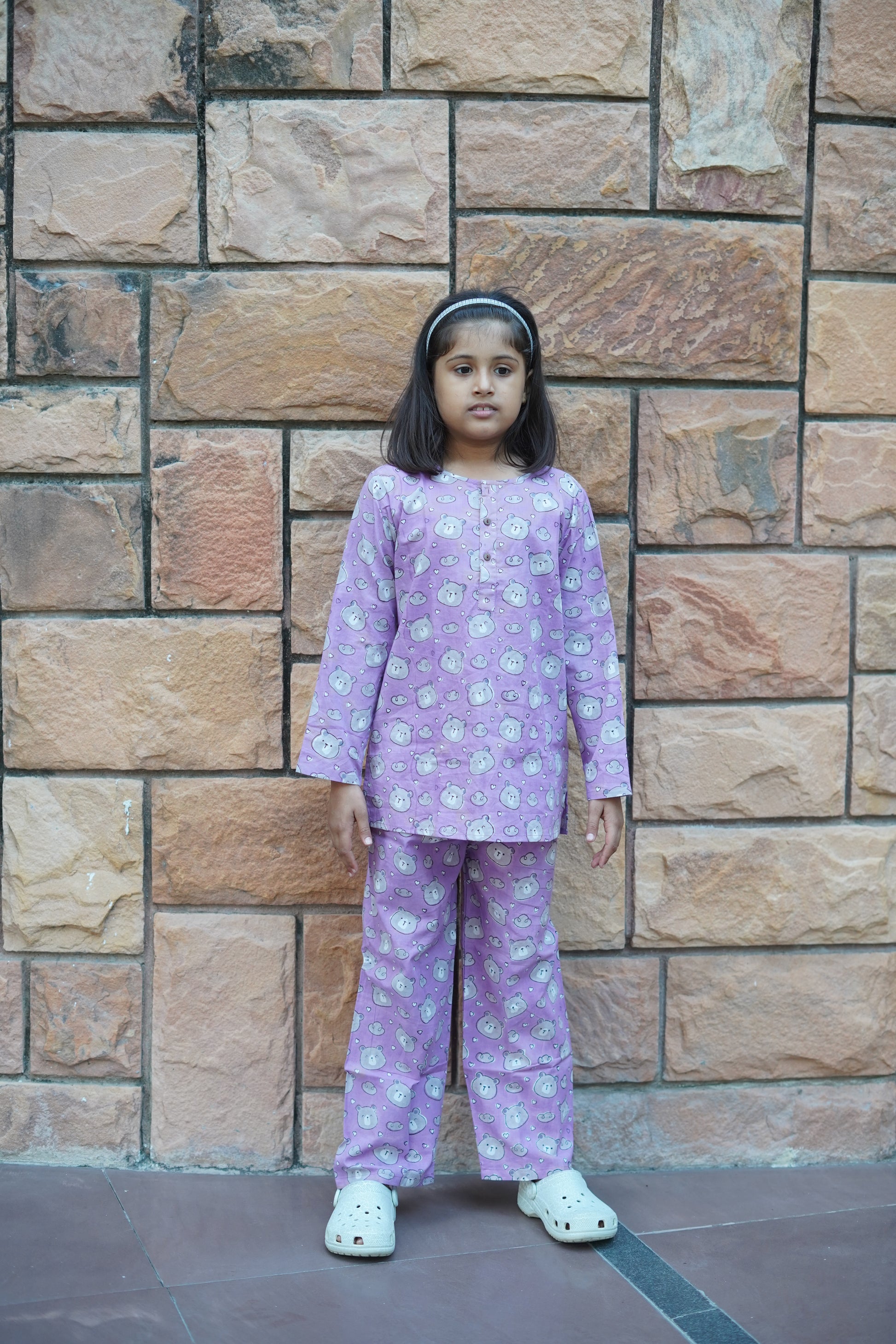 Child in a purple outfit standing on a stone floor