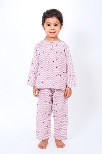 A child wearing a long-sleeved purple night suit with fish and wave patterns, consisting of a night shirt and pajama pants.